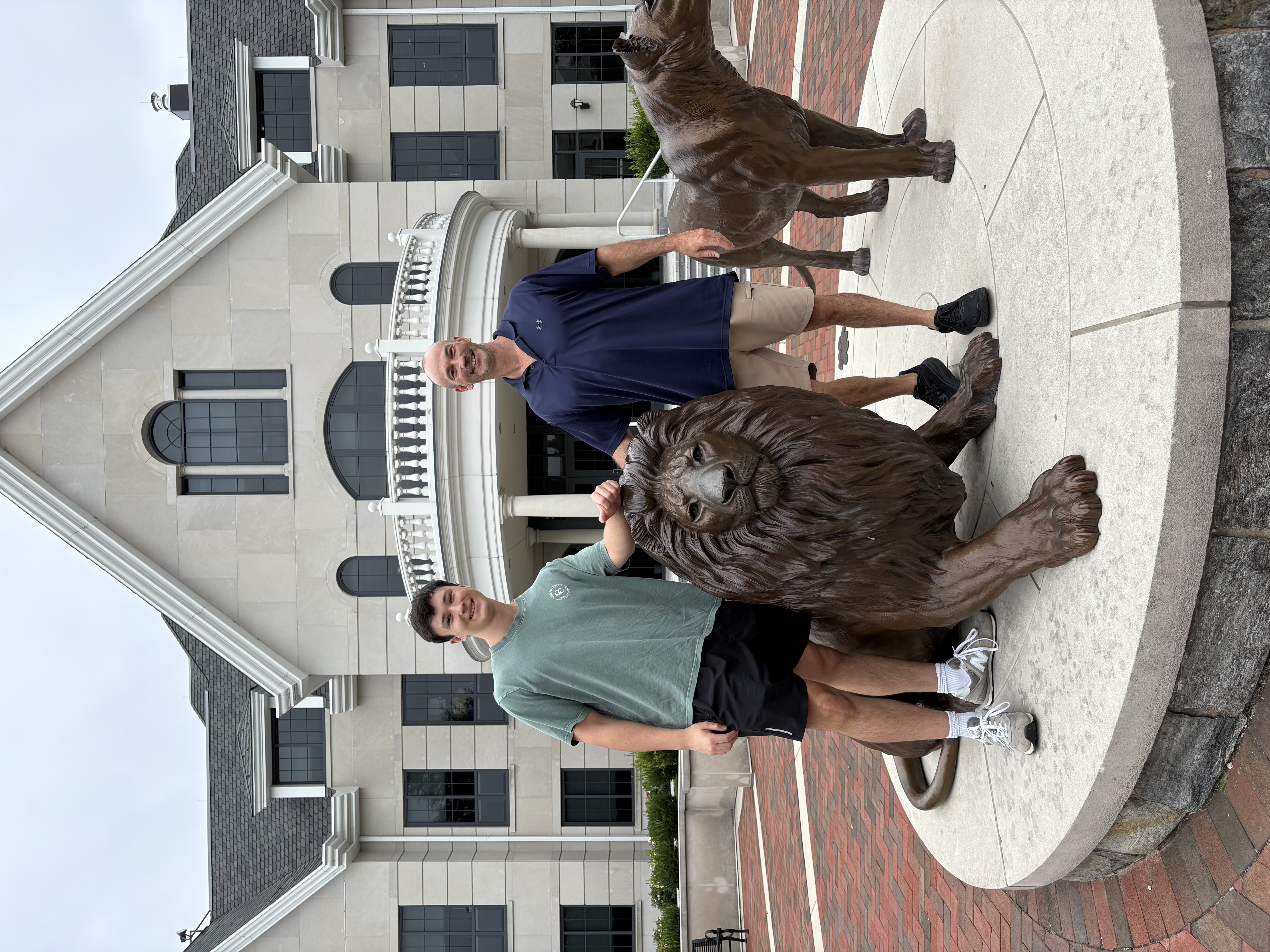 Student and his father standing with the Widener lion mascot statues