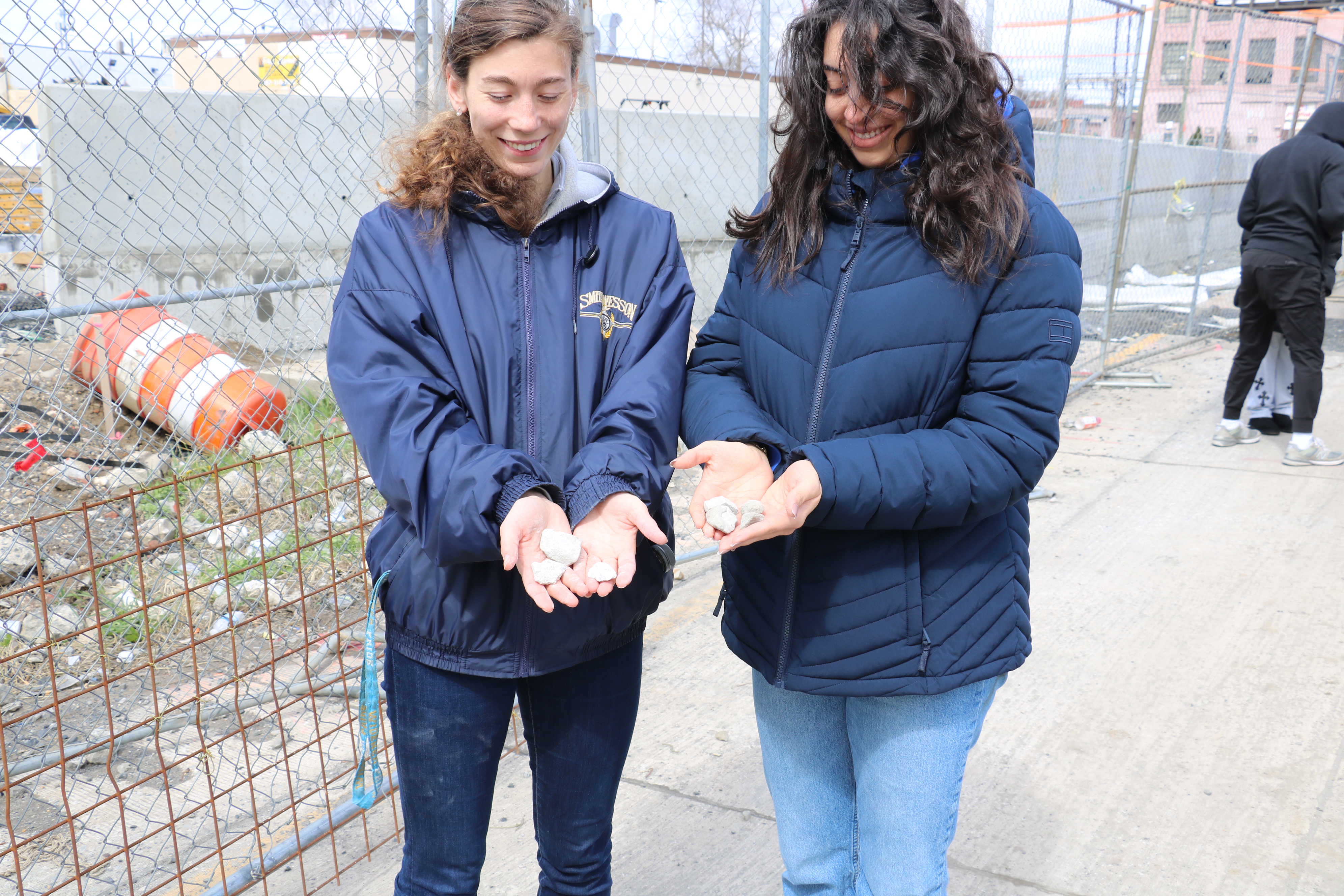 Two female students hold samples of building materials.