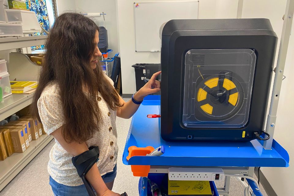 Lydia Aruffo standing next to Widener's 3D printer