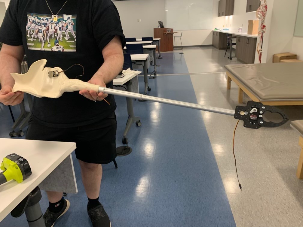 Student holding a robotic arm reacher