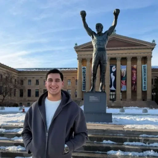 Cihan Uz standing in front of the Rocky Statue at the Philadelphia Museum of Art