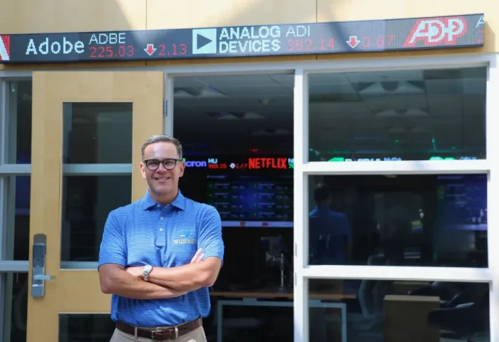 Cary Caro poses in front of the university's finance lab