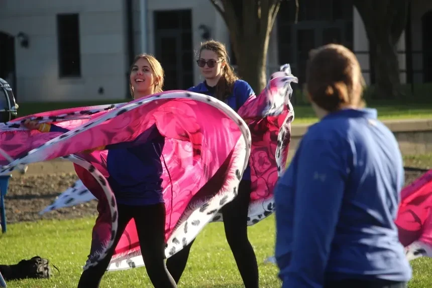 Color guard waving pink flags.