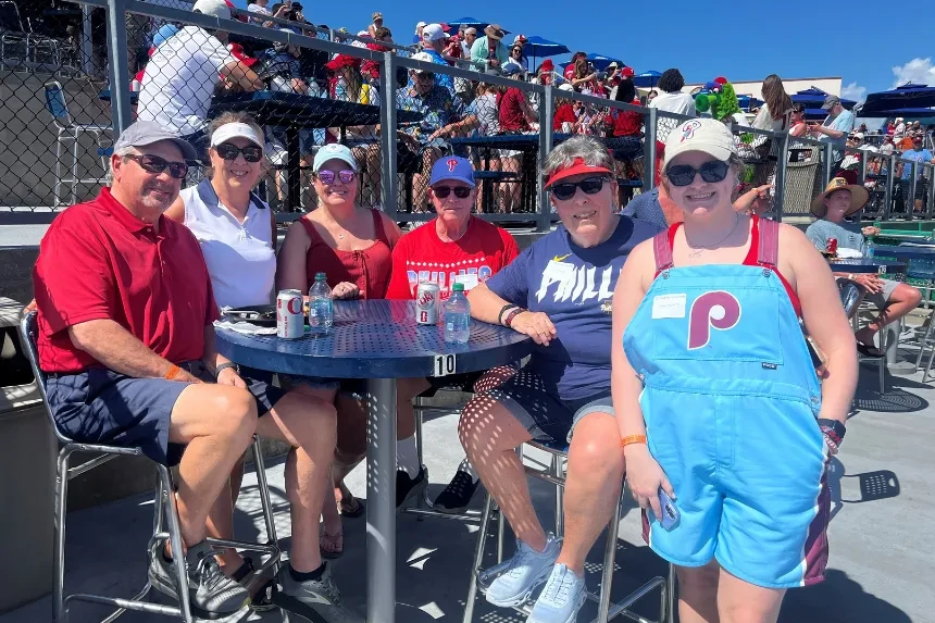 Alumni pose for a photo wearing Phillies gear at the ballpark
