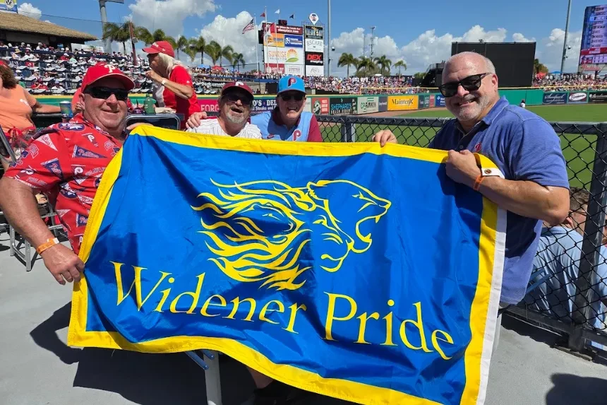 Alumni and Widener staff pose for a photo with a "Widener Pride" flag
