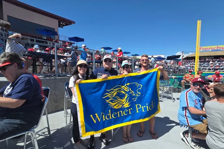 Alumni and Widener staff pose for a photo with a "Widener Pride" flag