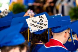 A graduate wearing a cap that says On to the Next Chapter