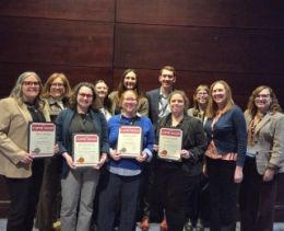 Eleven members of University Relations standing together holding awards certificates