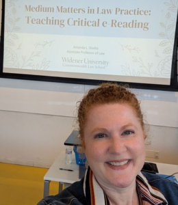 A selfie of Amanda Sholtis with her presentation on a screen behind her.