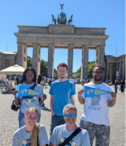 Widener students and faculty pose for a photo in Germany wearing Widener shirts and holding Widener banenrs.