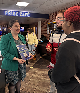Two students talk to an administrator outside the Pride Cafe dining hall