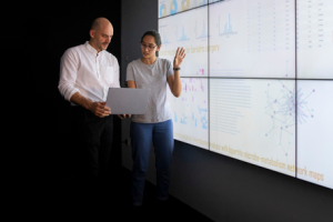 Two health care professionals presenting research in front of a large projection screen