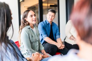 A group of young professionals in a seminar setting discussing a common topic