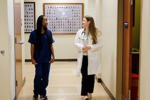 widener school of nursing graduate student in lab coat talks to undergraduate nursing student in health care office near philadelphia