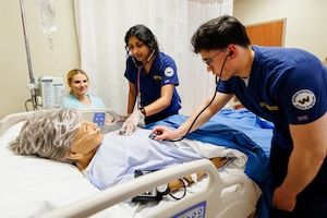 two widener undergraduate nursing students treat patient in the simulation lab while their professor advises them