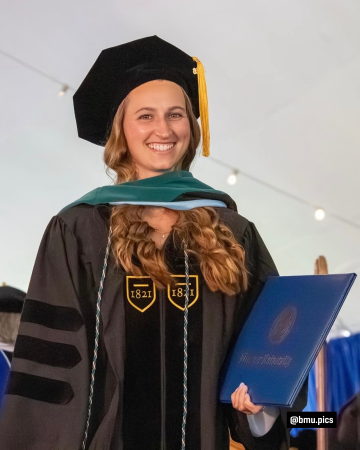 Student Gabby Nye in black grad cap and gown holding a blue Widener diploma folder