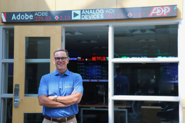 Cary Caro poses in front of the university's finance lab