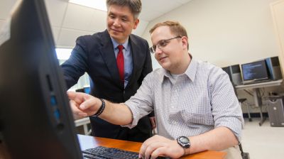 Professor working with a computer science student during a hands-on computer lab session.