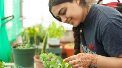 student with plants in greenhouse