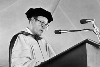 Black and white photo of Fitz Dixon in academic regalia speaking at a podium