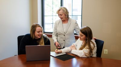 widener school of nursing professor mentors two nursing doctorate students working on a computer in an office