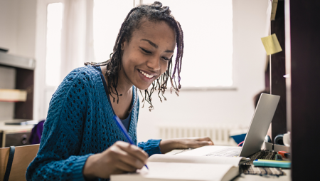Adult graduate student taking notes while on a computer