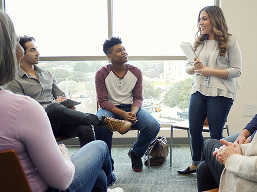 Social worker leading group session with 4 people present