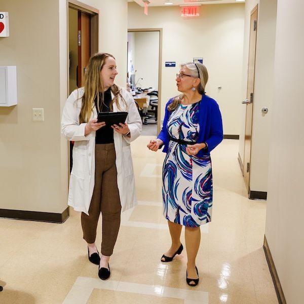 widener school of nursing graduate student wearing lab coat talks to professor in medical office near philadelphia