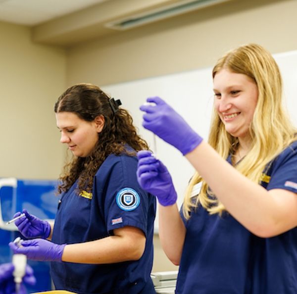 widener school of nursing undergraduate students wearing blue scrubs prepare vaccines in simulation lab