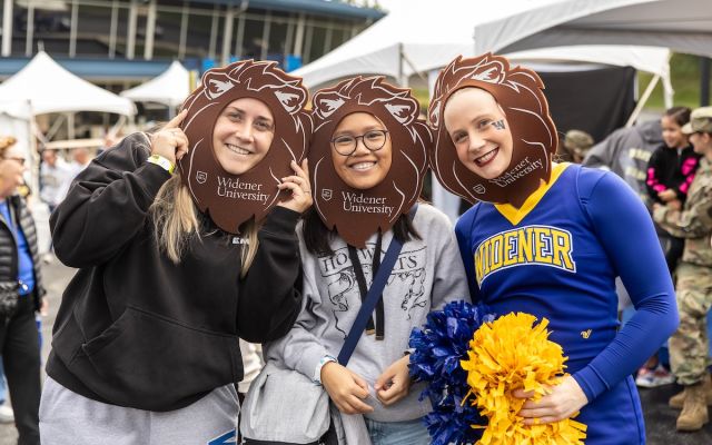 A group of students smiling at Widener's homecoming with foam lion manes.