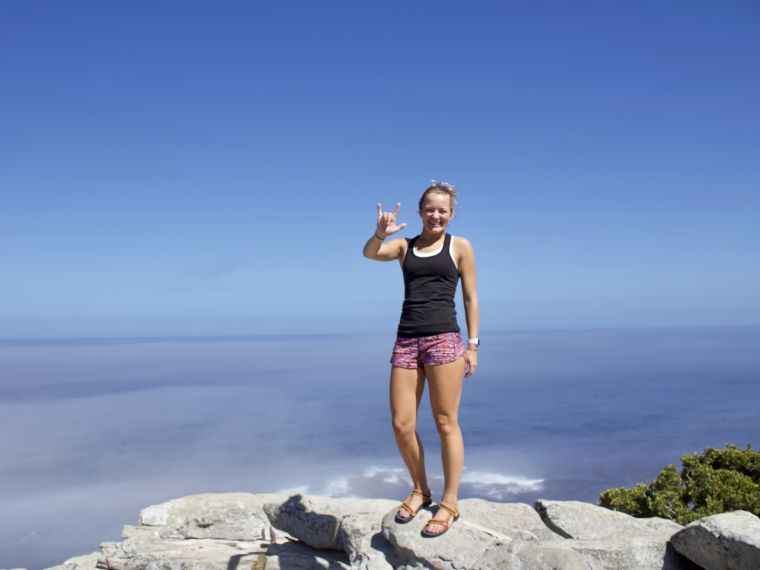 Hannah Berard stands on top of a mountain and signs "I love you"