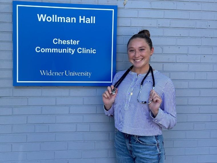 Taylor Wise poses in front of the Chester Community Clinic with her stethoscope draped around her neck.